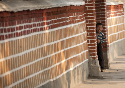 Smiling North Korean boy looking out in the entrance of his house, North Hwanghae Province, Kaesong, North Korea