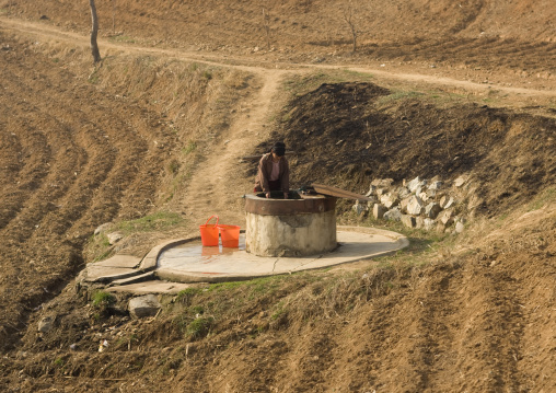 North Korean woman collecting water in a well in the countryside, South Pyongan Province, Nampo, North Korea