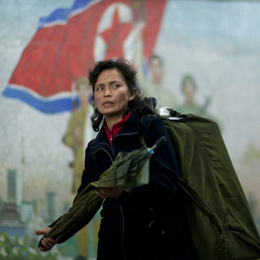North Korean woman in the subway in front of a propaganda mosaic, Pyongan Province, Pyongyang, North Korea