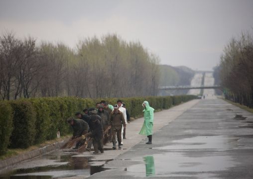 North Korean men repairing holes on an empty highway under the rain, Pyongan Province, Pyongyang, North Korea