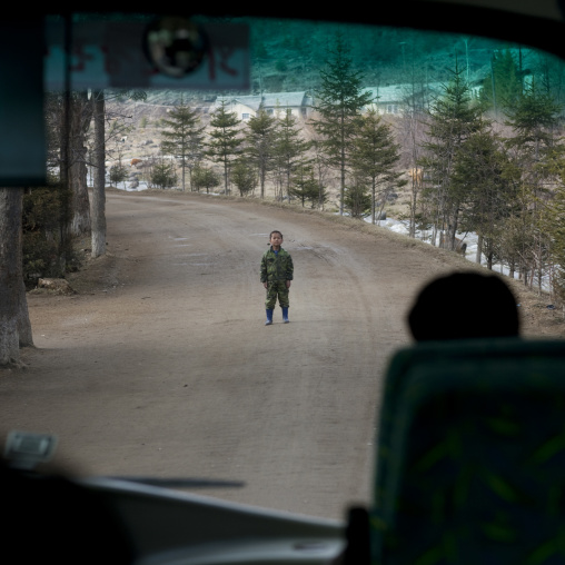 North Korean boy standing in the middle of the road in front a bus, Ryanggang Province, Rimyongsu, North Korea