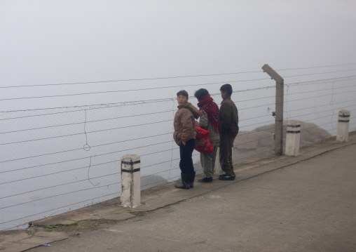 North Korean people looking through barbed wire on the coastline in the fog, Kangwon Province, Wonsan, North Korea