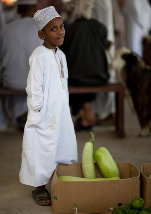 Boy In Dishdasha Standing Beside A Box Of Vegetables, Sinaw, Oman