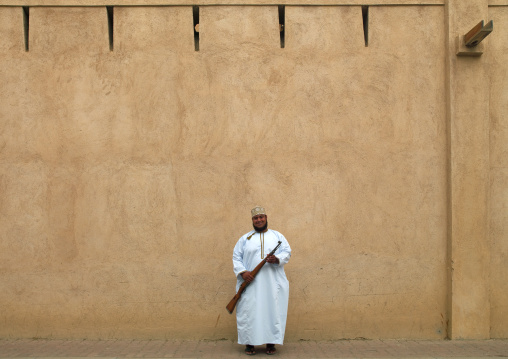A Man Back From Weapon Market Standing In Front Of The Wall, Nizwa, Oman