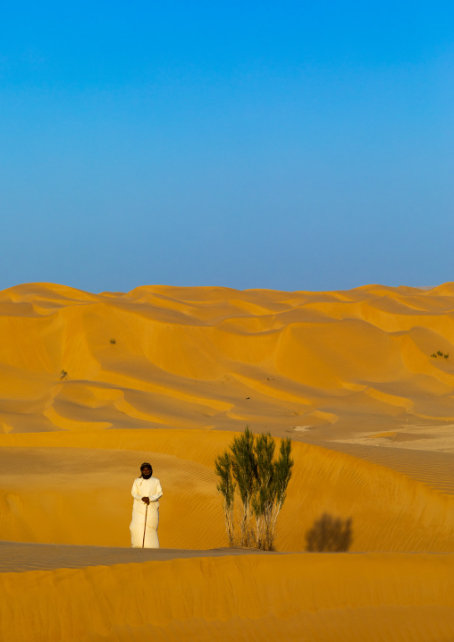 Omani man standing near a tree in the rub al khali desert, Dhofar Governorate, Rub al Khali, Oman