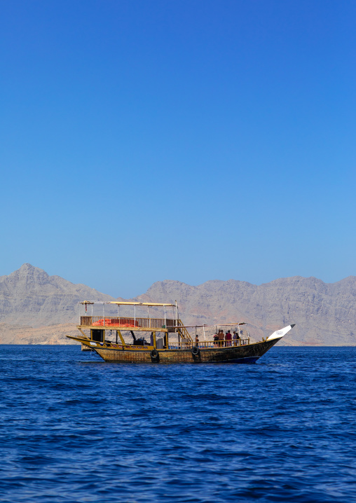 Dhow sailing in the fjords in front of mountains, Musandam Governorate, Khasab, Oman