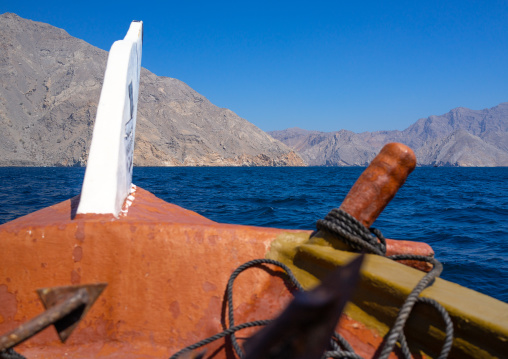 Dhow sailing in the fjords in front of mountains, Musandam Governorate, Khasab, Oman