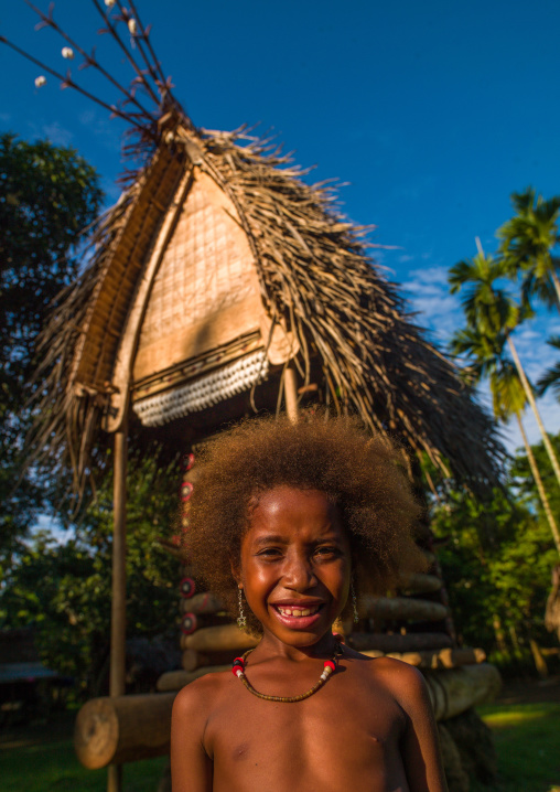 Girl in front of a yam house in a village, Milne Bay Province, Trobriand Island, Papua New Guinea