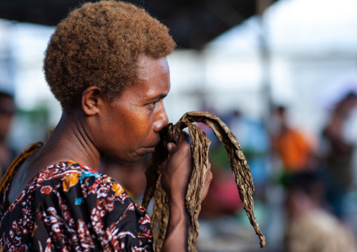 Woman smelling tobacco in a market, East New Britain Province, Rabaul, Papua New Guinea