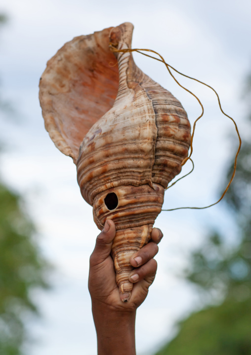 Boy holding two giant shells used to call friends, Milne Bay Province, Alotau, Papua New Guinea