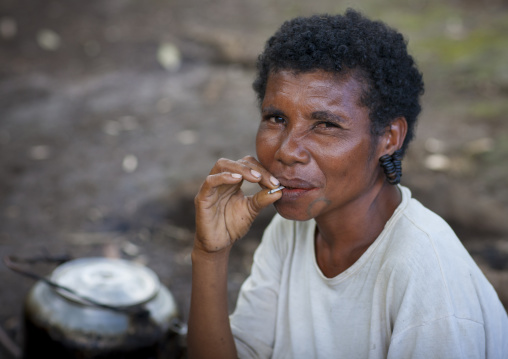 Woman with earrings made with turtle shells smoking, Milne Bay Province, Trobriand Island, Papua New Guinea