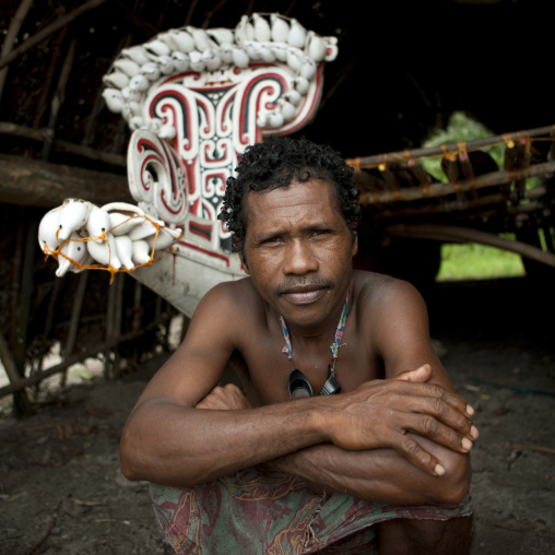 Man in front of kula canoe decorated with shells, Milne Bay Province, Trobriand Island, Papua New Guinea