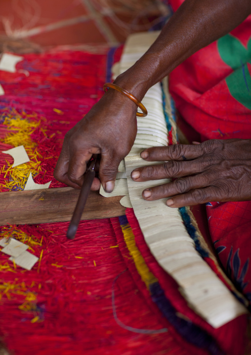 Woman making a traditional skirt with pandanus and banana leaves, Milne Bay Province, Trobriand Island, Papua New Guinea