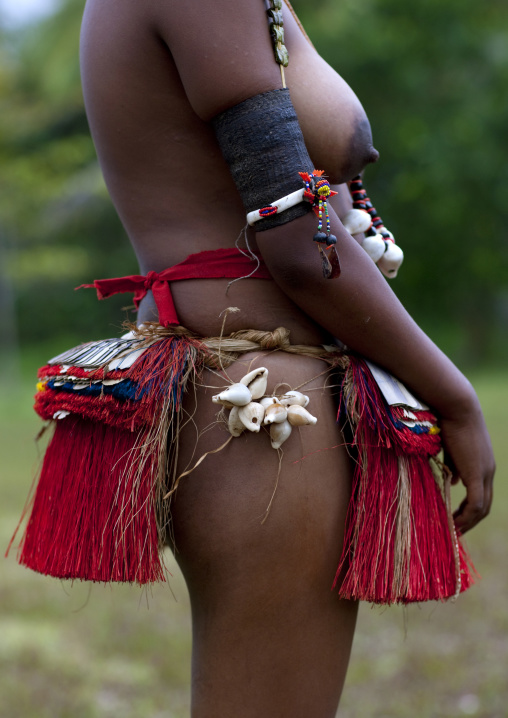 Topless woman wearing a traditional red grass skirt, Milne Bay Province, Trobriand Island, Papua New Guinea