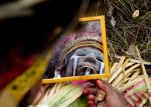 Melpa tribe woman looking in a mirror during a sing sing, Western Highlands Province, Mount Hagen, Papua New Guinea