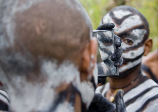 Snake man during a sing sing looking at himself in a mirror, Western Highlands Province, Mount Hagen, Papua New Guinea