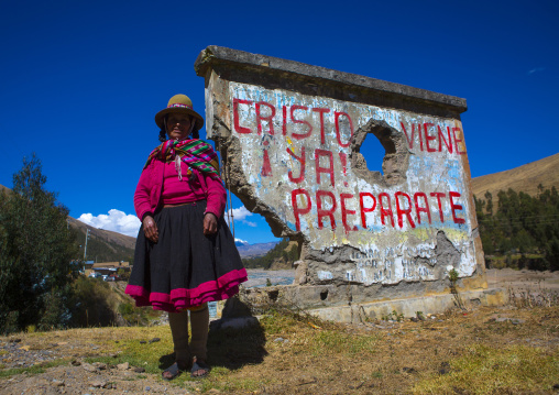 Perivian Woman In Front Of A Catholic Slogan, Cuzco, Peru