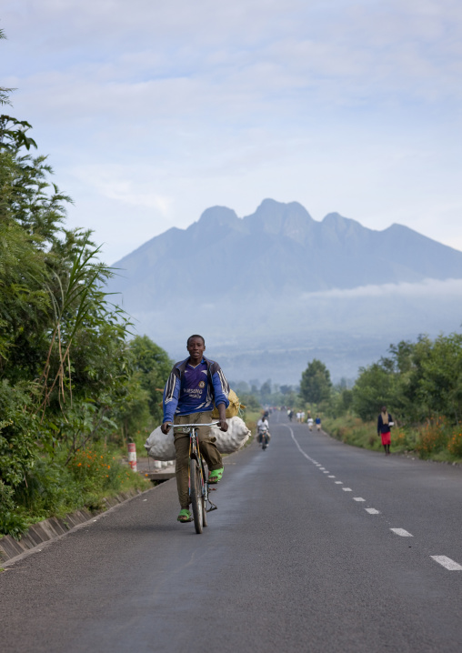 Rwandan man riding a bicycle on the road leading to the volcano, Northwest Province, Rehengeri, Rwanda