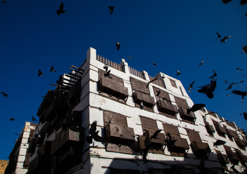 Pigeons flyiing over an old house with wooden mashrabiya in al-Balad quarter, Mecca province, Jeddah, Saudi Arabia