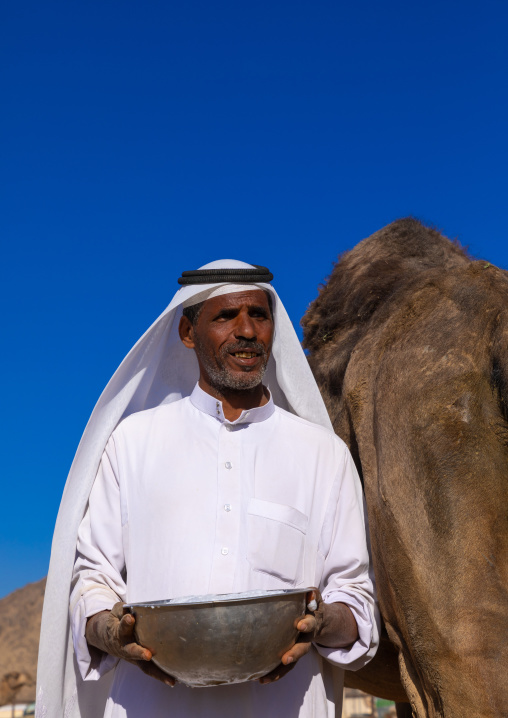 Saudi man holding a bucket of fresh camel milk, Najran Province, Najran, Saudi Arabia