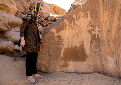 Tourist looking at petroglyphs of Aliya the goddess of fertility, Najran Province, Thar, Saudi Arabia