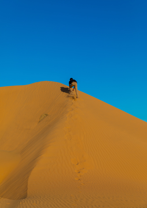 Tourist climbing a sand dune in the Rub' al Khali empty quarter desert, Najran province, Khubash, Saudi Arabia