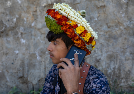 Portrait of a flower young man calling on his mobile phone and wearing a floral crown on the head, Jizan Province, Addayer, Saudi Arabia