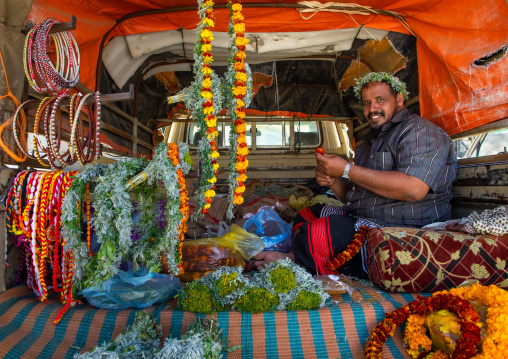 A flower vendor preparing floral garlands and crowns on a market in the back of his car, Jizan Province, Addayer, Saudi Arabia