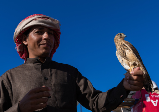 Saudi man with a falcon perching on hand in a bird market, Najran Province, Najran, Saudi Arabia