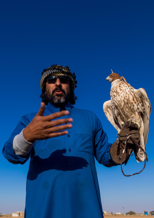 Saudi man with falcon perching on hand, Al-Jawf Province, Sakaka, Saudi Arabia
