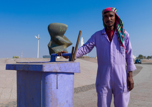 Pakistani worker with a bin near modern art on the corniche, Hijaz Tihamah region, Jeddah, Saudi Arabia