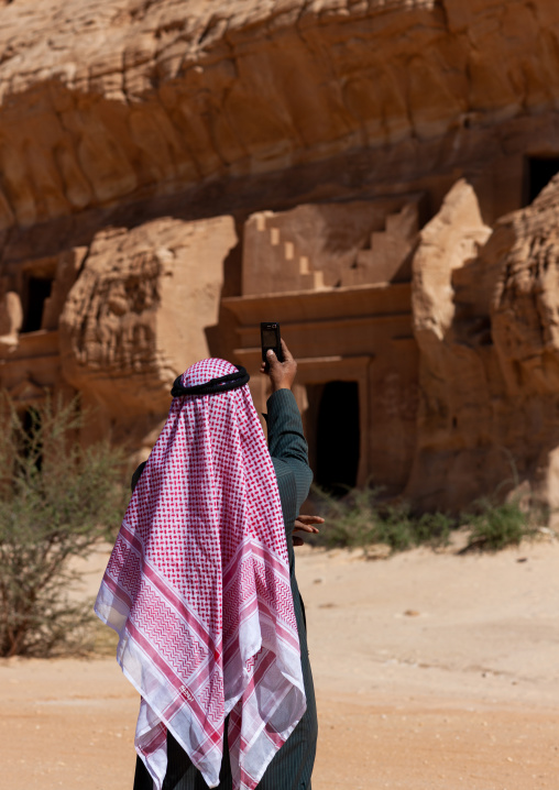 Saudi tourist taking a picture of a nabataean tomb in madain saleh archaeologic site, Al Madinah Province, Al-Ula, Saudi Arabia