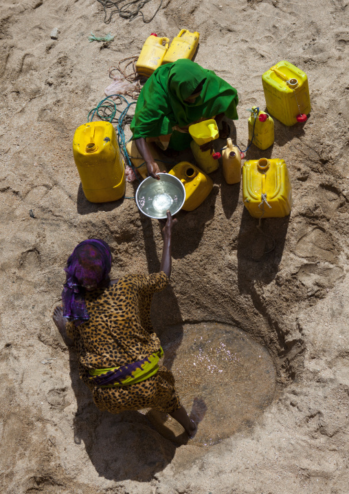 Women Taking Drinking Water From A Well Hole In The Sand And Pouring It Into Plastic Containers, Lasadacwo Village, Somaliland