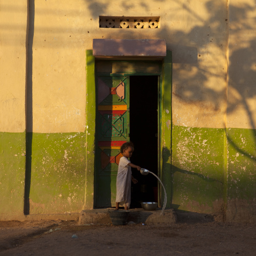 Young Girl Throwing Water Outside The Doorway Of A Painted Door House, Burao, Somaliland