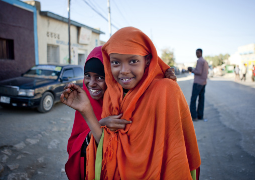 Two Teenage Girls Wearing Orange And Red Hijabs Laughing At The Camera On A Street, Boorama, Somaliland