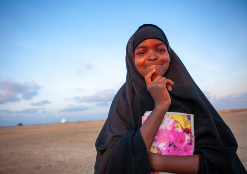 Portrait of a somal girl in black veil with a school book, Awdal region, Zeila, Somaliland