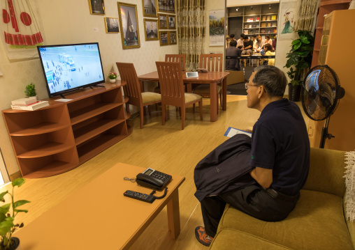 South Korean visitor looking at television during the exhibition Pyongyang sallim at architecture biennale showing a north Korean apartment replica, National Capital Area, Seoul, South Korea
