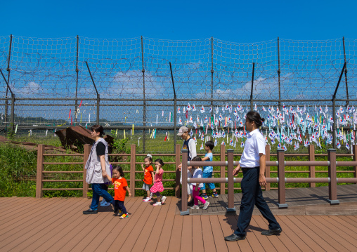 South Korean family passing in front of messages of peace and unity written on ribbons left on fence at DMZ, North Hwanghae Province, Panmunjom, South Korea
