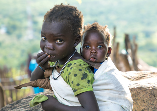Lotuko tribe girl carrying her sister on her back, Central Equatoria, Illeu, South Sudan