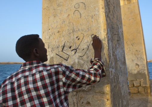 Sudan, Port Sudan, Suakin, man writing on the wall of a ruined ottoman coral buildings