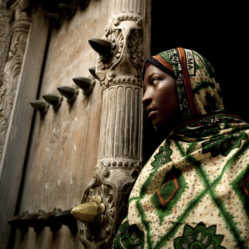 Swahili girl standing in front of  an old door in stone town zanzibar, Tanzania