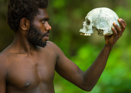Man holding a human skull in Amelbati cannibal site, Malampa Province, Malekula Island, Vanuatu