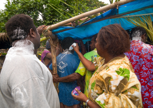 Women putting flour on people queueing to meet the bride and the groom during a traditional wedding, Malampa Province, Ambrym island, Vanuatu