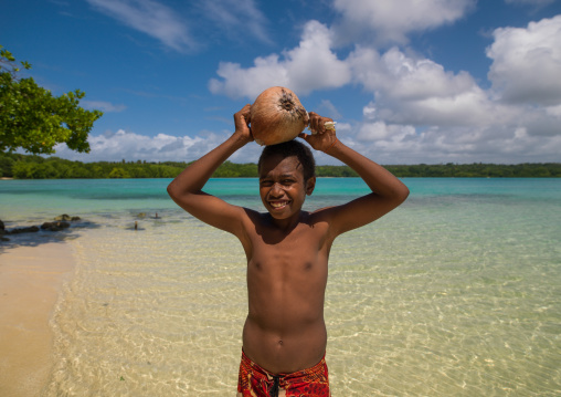 Young boy of the Ni-Vanuatu people with a coconut on his head, Sanma Province, Espiritu Santo, Vanuatu