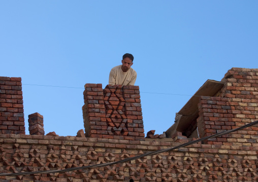 Man Chewing Qat While Adjusting Bricks On A Roof, Sanaa, Yemen