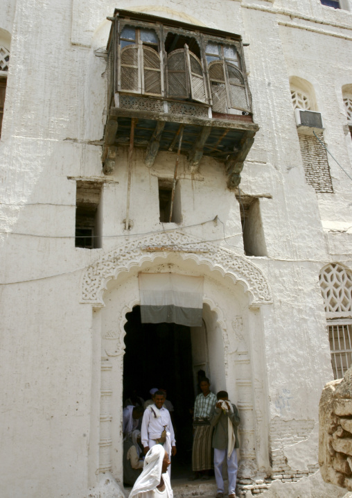 Men Standing At The Door Of A Builing Under A Mashrabiya And A Yemeni Flag With Faded Colours, Zabid, Yemen