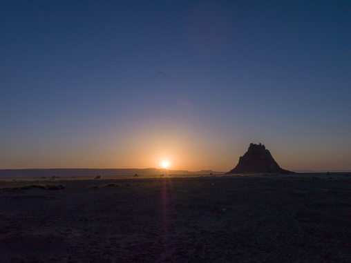 The sun sets behind a lone limestone chimney rising from the desert plain, Afar depression, Lake Abbe, Djibouti