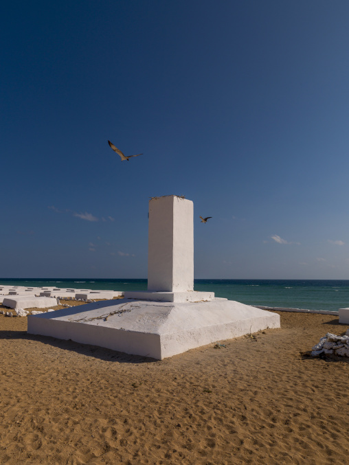 Two birds fly above a memorial obelisk in a French colonial marine cemetery, Obock Region, Obock, Djibouti