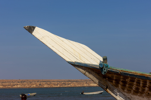 The pointed wooden bow of a dhow rises above a coastal bay, Obock Region, Obock, Djibouti