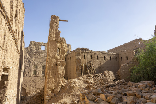 Rubble and collapsed walls of a ruined mudbrick village beneath a clear blue sky, Ad Dakhiliyah Region, Al Hamra, Oman